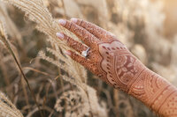 Close-up of bridal mehndi design and diamond engagement ring during South Asian wedding portraits at golden hour.