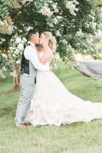 bride and groom kissing in front of crepe myrtle tree at spinning leaf wedding venue