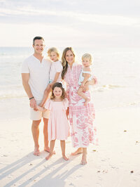 Family of five standing together on the beach with ocean in the background