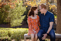 Heartwarming autumn portrait of dad and teen daughter on a park bench framed by colorful foliage at Ballantyne Corporate Park