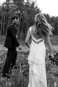 bride and groom walking through a field