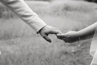 Wife and husband holding hands during their wedding photos in a rural field in Minnesota