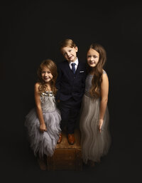 Studio family portrait in Austin, Texas, capturing a joyful family of three with genuine smiles, soft lighting, and a warm, welcoming atmosphere that showcases their close bond.