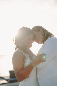 two women embracing while standing in front of water