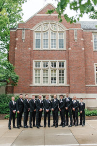 groom with groomsmen outside brick building