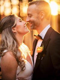 Groom wearing a foresto tuxedo pulls his bride in closely as they close their eyes and lean in for a kiss during their wedding at The Village Club at Lake Success.