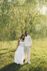 a couple pose under a tree for their engagement photos