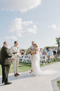 Guests gathered along the ceremony aisle at sunny outdoor destination wedding, photographed by Clar Barron Photo.