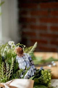 Floral stems on a table in front of a brick wall