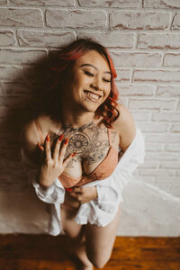 woman with tattoo in her chest leaning on the wall
