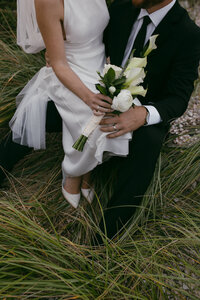 bride sitting on groom's knee in the middle of a field