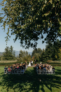 Bride holding her wedding bouquet high in the air with flowing white ribbons, captured by a Washington wedding photographer.