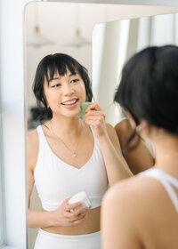 Woman looking in the mirror with skin care tool