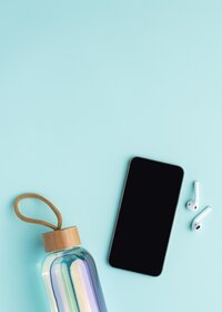 Teléfono y audífonos con botella de agua sobre fondo aqua.