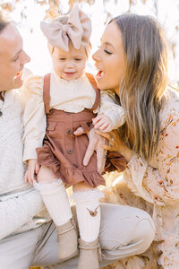 Mom and Dad playing with their young daughter in the fall; Kansas City family photography by Jeanna Hayes