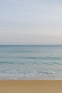 Calm ocean horizon and sandy beach representing peaceful travel destinations. Tailored Oasis Travel Co.