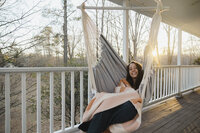 Katie sits in a hammock on a porch.