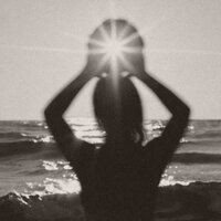 Silhouette of a person holding light between hands at sunset, symbolizing spiritual connection and awakening.