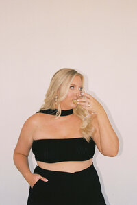 An image of wedding photographer Leslie DeAnn sipping from a wine glass in a black top