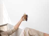 Girl holding cup of coffee and glasses and lying