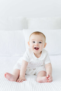 Baby sitting up smiling at the camera for milestone photography session