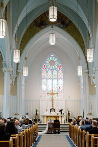 The interior of a church with a large stained glass window with a cross underneath