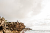 bride and groom holding hands walking toward edge of cliff