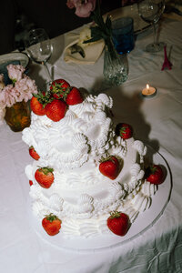 A beautifully vintage wedding cake adorned with fresh strawberries, showcasing the charm of simple, authentic wedding details. This candid shot highlights the importance of capturing timeless elements in documentary wedding photography across Pennsylvania, reflecting the genuine essence of a couple's special day