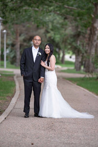 A bride stands by her groom holding on to his arm. University of saskatchewan in Saskatoon.