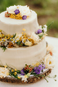 wedding cake decorated with fresh flowers sitting on a white table