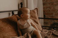 a profile shot of a baby boy on a bed in a beautiful studio in rochester, ny
