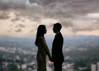 Brisbane Registry Office wedding couple silhouetted in front of large city-view window, holding hands after their ceremony.