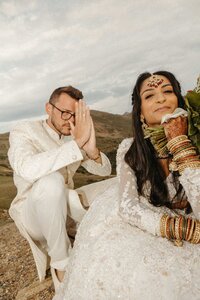 A couple posing on a mountain top after their elopement in South Asian outfits
