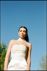 A 35mm film photo of a bride with a blue sky background in an editorial style.