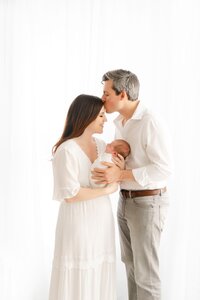 parents kissing posed with newborn baby by Boston Newborn Photographer