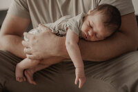 Neugeborenes kuschelt auf Elterns Arm – Newbornshooting in Aachen