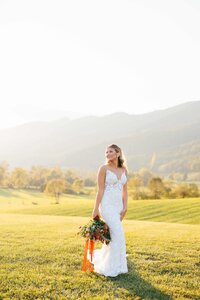 Bride smiling into distance with bouquet at side at crooked river venue