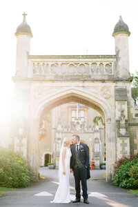 bride and groom stood outside tortworth hall with the sun behind them