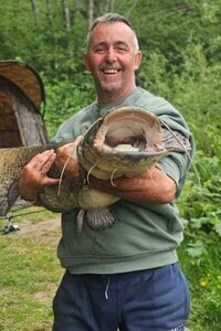 Smiling boss Scott holding a large catfish outdoors.