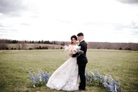 a bride and groom snuggle up to one another while standing within a semi-circle of flowers outdoors