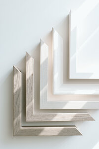 Three framed portraits stand together up against a wall with various textures and colors such as wood, metal, light wood