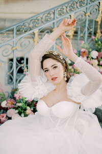 Elegant bridal portrait at a French Chateau with lush floral backdrop and puff sleeve gown