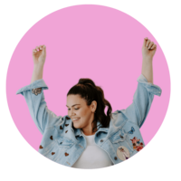 Woman with dark hair with arms up in the air on pink background