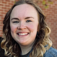 Jennifer McGraw smiling woman with blond hair purple shirt and gray scarf