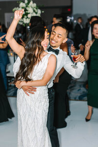 Bride and groom dancing at reception with arms around each other