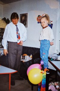 Dochter is jarig en staat op stoel met ballonnen en slingers en vader staat ervoor met stropdas om