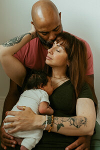 Couple hugging their newborn during studio photos in Kitchener, Ontario.