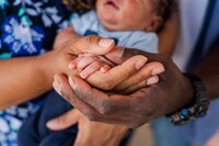Mom and dad hold baby's hand