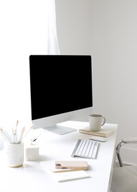 Mac on a desk with white accessories around it