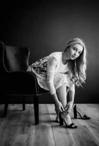 black and white blonde girl putting on heels in fancy chair